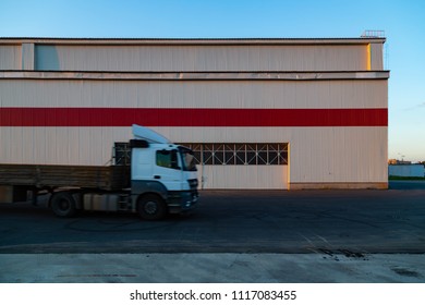 View of a modern white two-story warehouse factory and storage facilities near the road. Lawn fresh green grass. Sunset. Spring. Blue sky. Red and white - Shutterstock ID 1117083455