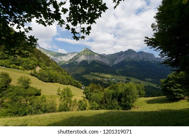 View of  Montmin nestled in the valley through tree foliage below Col de la Forclaz France