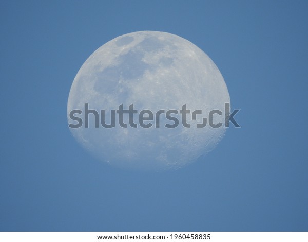 A view of\
moon with blue sky in the day time\
