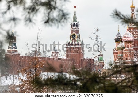 View of the Moscow Kremlin and St. Basil's Cathedral from Zaryadye Park in Moscow on a winter evening. Pine branches with snow are used as a beautiful photo frame. focus on the tower