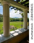 View of Mount Ascutney and  Connecticut River Valley. Purple iris, and Columbine flowers in the foreground. View from Little Studio at Saint-Gaudens National Historic Site. Colonnade and arbor.