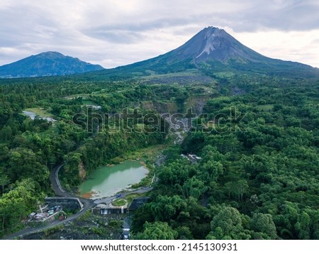 The view of Mount Merapi with the Bebeng River and a lake that holds water, the sky looks cloudy. Forest with dense of trees surrounding the lake also See Mt. Merbabu from a distance. Bego Pendem