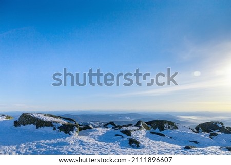 View from mount peak to mountain hills, white snow, blue sky, stones and fir trees. Winter landscape in Gornaya Shoria, Sheregesh ski resort in Russia, Altai mountains nature environment background.