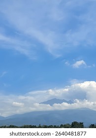view of a mountain covered in white clouds with a bright blue sky