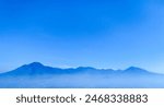 view of the mountain from a distance, with a blue gradient sky in the background and dew below