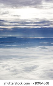 View of the mountain ridge and peaks with cloudy blue sky. The mountain covered with clouds and sun shine from the sky above to the sky bottom. Sunset scenery.