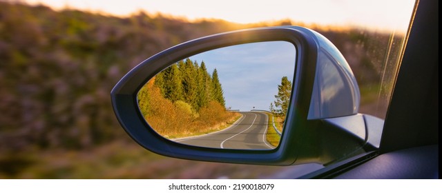 The view of the mountains in the car's rearview mirror. Travel by personal car, concept.