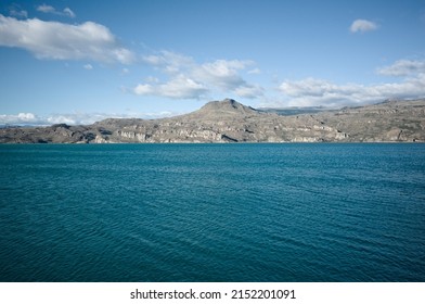 View of mountains from shore of Lago General Carrera Lake, Puerto Ibanez, Aysen Province, Chile. Summer day at glacial lake with clear bright blue water and light ripples on water in Chilean Patagonia