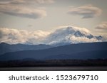 A view of Mt. Baker surrounded by clouds taken from Sandy Point, Washington. Mt. Baker is a mountain in the North Cascades. 