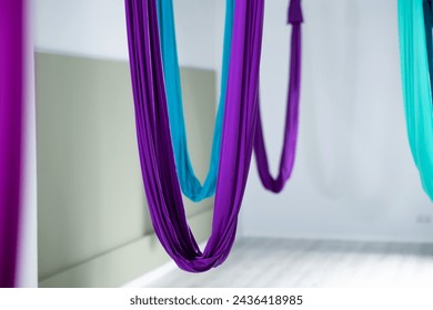 View of multicolored suspended silk hammocks for aerial or anti-gravity yoga in empty modern fitness studio. Popular leisure, recreation, sports activity and wellness concept.. - Powered by Shutterstock