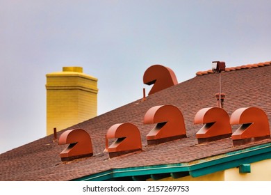 View of multiple goose neck vents on top of a slanted shingles roof top.