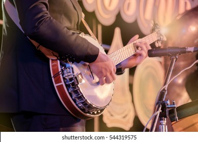 View Of Musician Playing Banjo In Concert At Night. Movement. Shallow Depth Of Field.