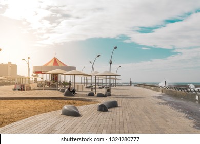 View of Namal promenade at Tel Aviv Port, Israel. Sunset at harbour deck with carousel and sunshades by the sea