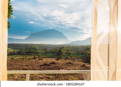 View Of Nature Of Mountain By Window White Curtain By The Window Look Through The Curtains With Light From The Sunset, The Atmosphere Of Relaxation At Living Room In A Holiday Close To Natural.