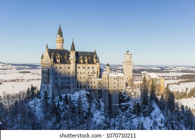 View Of Neuschwanstein Castle From  Queen Mary's Bridge Surrounded By Trees And Snow