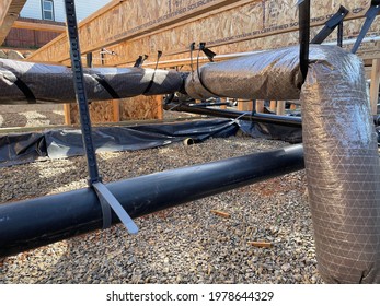 View Of New Installation Of Ventilation Ductwork And Plumbing Pipes From Inside The Crawlspace And Under The Open Floor Trusses Of A New Home Construction Project