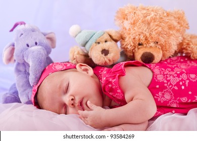 View Of A Newborn Baby On Smooth Bed With Stuffed Toy Sleeping.