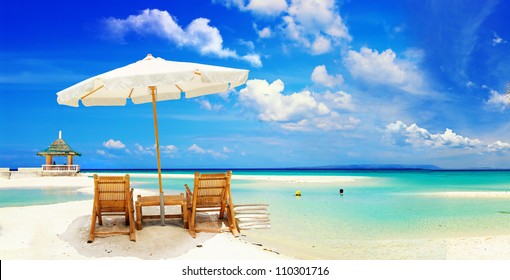 View of nice tropical empty sandy beach with umbrella and beach chair - Powered by Shutterstock