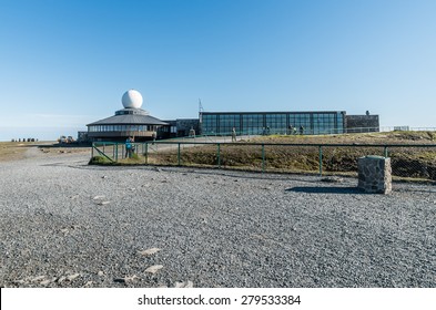 A view of Nordkapp Visitors Centre taken from the monument under a clear blue sky.