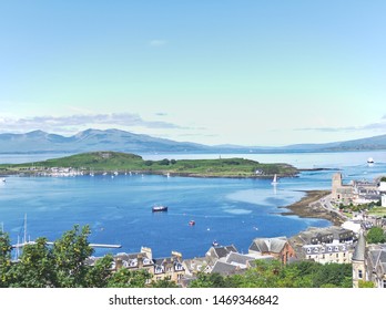 View of Oban bay in Scottish highlands with sailing and fishing boats and mountain backdrop