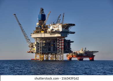 View of offshore oil and gas installation in a sunny day in sea. 
Jack up, semi submersible rigs crude oil production in ocean.