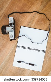 View of an old camera and a notebook on wood desk