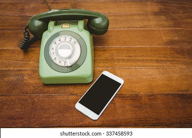 View Of An Old Phone And A Smartphone On Wood Desk