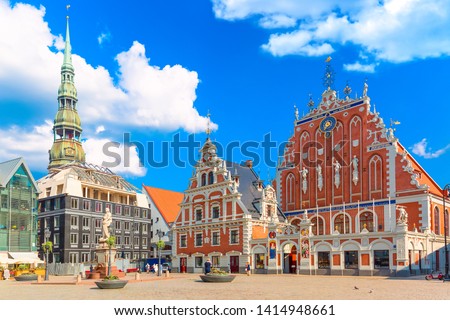 View of the Old Town Ratslaukums square, Roland Statue, The Blackheads House and St Peters Cathedral against blue sky in Riga, Latvia. Summer sunny day.