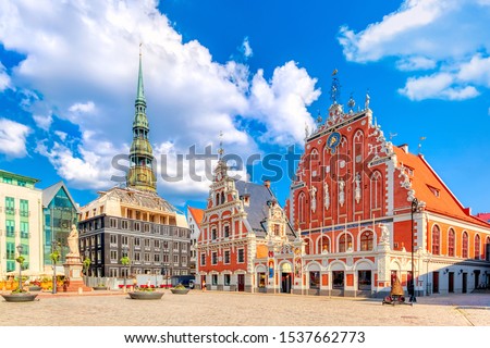 View of the Old Town Ratslaukums square, Roland Statue, The Blackheads House and St Peters Cathedral against blue sky in Riga, Latvia. Summer sunny day.