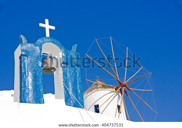 The View  of old  white mill and white chapel ion the background of the blue sky on Santorini island in Greece                                