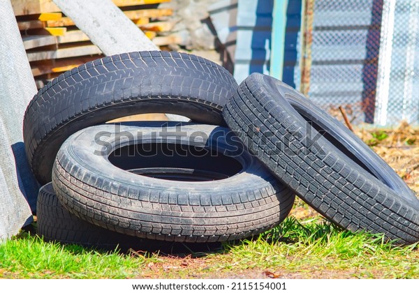 view of old worn\
out wheels, rubber tires from a car with a worn tread lying in the\
yard of a house, cottage