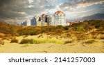View on belgian modern coast town buildings lonely in the sand dunes against dramatic autumn cloudy overcast sky storm clouds - Knokke - Heist, Belgium 