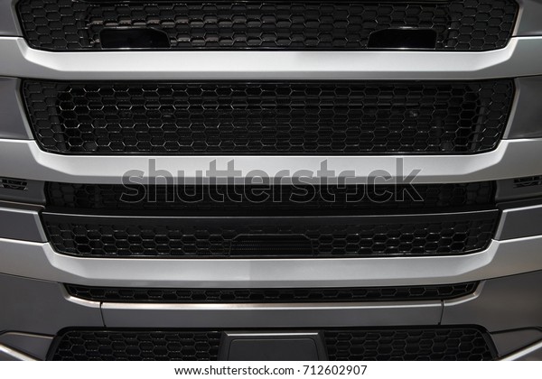 View on car truck cabin radiator cover with grid\
grille. Car radiator grille background pattern. Gray truck hood\
cabin front cover engine access inspection maintenance. Truck face\
cabin cover hood