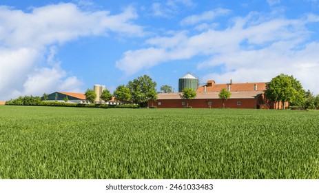 View on cattle or pig farm with silo storage and feeding system. Rural Germany landscape with field, buildings, blue sky and clouds in sunny day. - Powered by Shutterstock