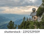 View on a charming small mountain chapel built on the edge of a mountain cliff overlooking the valley in the austrian Alps on Stoderzinken mountain. Dachstein mountains.