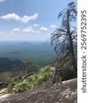 View on a cliff of rocks on a mountain during a hiking trip in South Carolina. The horizon overlooks many other mountains and park nature views. The view is close to the clouds. Sunny summer day.