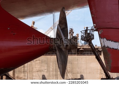 View on the container ships propeller. Ship is inside a dry dock for routine maintenance and painting.