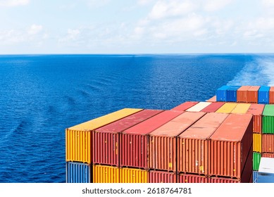 View on the containers loaded on deck of the large cargo ship. She is sailing through calm, blue ocean.