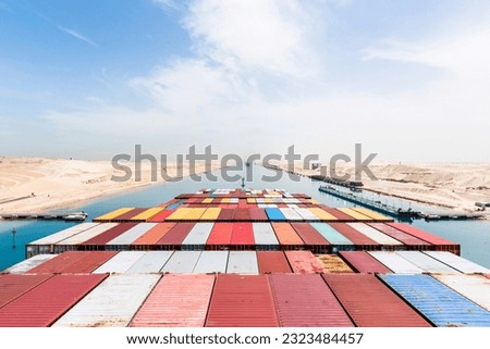 View on the containers loaded on deck of cargo ship. Vessel is transiting Suez Canal on her international trade route. Suez canal landscape.