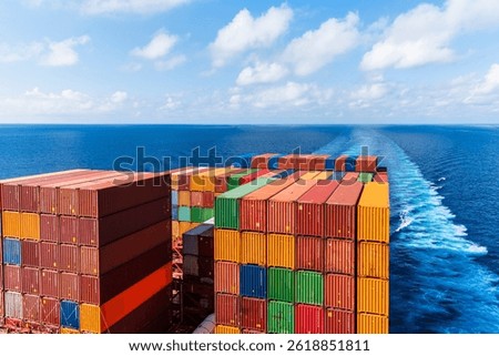 View on the containers loaded on deck of the large cargo ship. She is sailing through calm, blue ocean.