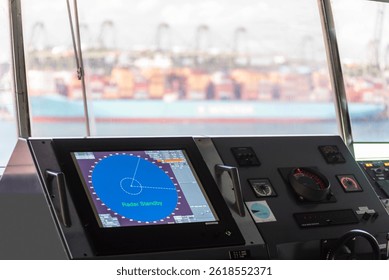 View on the control console, with radar display, of the container ship. She is berthed under gantry cranes for loading and unloading cargo on her international route. 