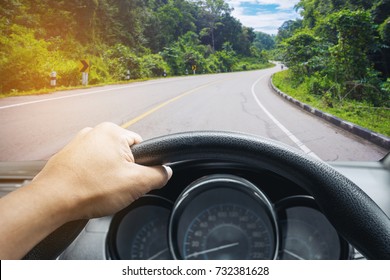 View On The Dashboard Of The Truck Driving.The Driver Is Holding The Steering Wheel. Forest Road Is In Front Of The Car.