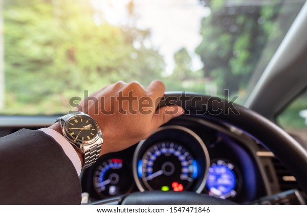 View\
on the dashboard of the truck driving.The driver is holding the\
steering wheel. Forest road is in front of the\
car