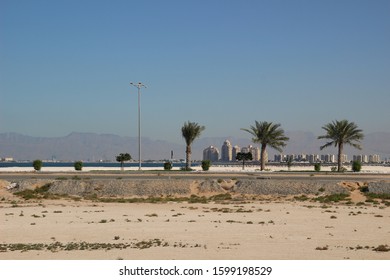 The view on desert, road, palm trees, sea, city buildings, mountains in Ras-Al-Khayma in bright sunny day