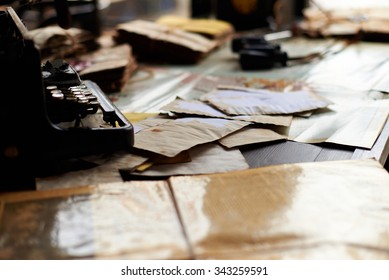 View On A Desk In A Old Military Office. A Stack Of Old Letters Tied With Laces, Typewriter Old Yellow Paper, Binoculars, Ash Tray Lying On A Map, Telephone.  Shallow Depth Of Field.