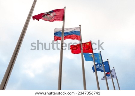 View on the flags of China, Kazakhstan, South Korea, Russia, Commonwealth of Independent States, coat of arms of Moscow on the background of cloudy sky