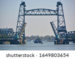 View on the former railway bridge, Koningshavenbrug (de Hef) in Rotterdam, The Netherlands, with bridge decks of Koninginnebrug open for ship and sailboat