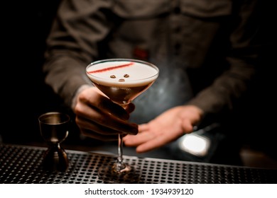 view on glass in male bartender hands with tasty espresso martini cocktail decorated with coffee beans