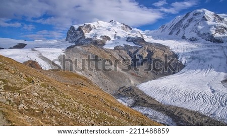 View on Gorner glacier on the left, Border Glacier Grenz Gletscher on the right, both framing the Monte Rosa massif in the middle. Male on a hiking trail to the Monte Rosa mountain hut. Zermatt.