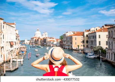 View on Grand canal with woman traveler in hat on Academia bridge in Venice. Back view with copy space